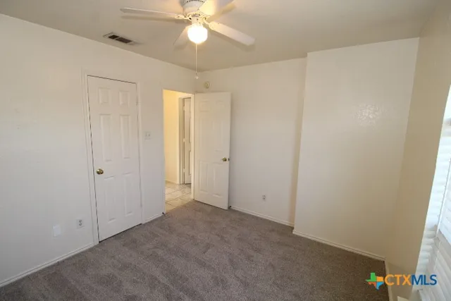 an empty room with a ceiling fan and a window