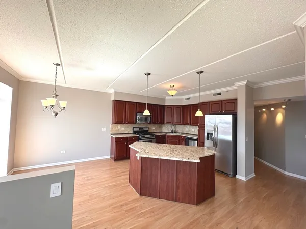 a large kitchen with stainless steel appliances kitchen island a large counter top and wooden floors