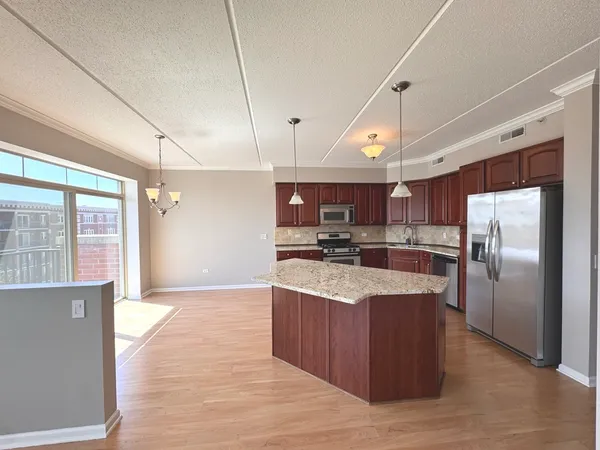 a large kitchen with stainless steel appliances kitchen island granite countertop a large counter top and wooden floors
