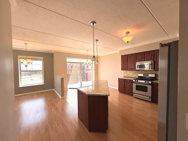 a kitchen with stainless steel appliances kitchen island granite countertop a stove a sink and a refrigerator