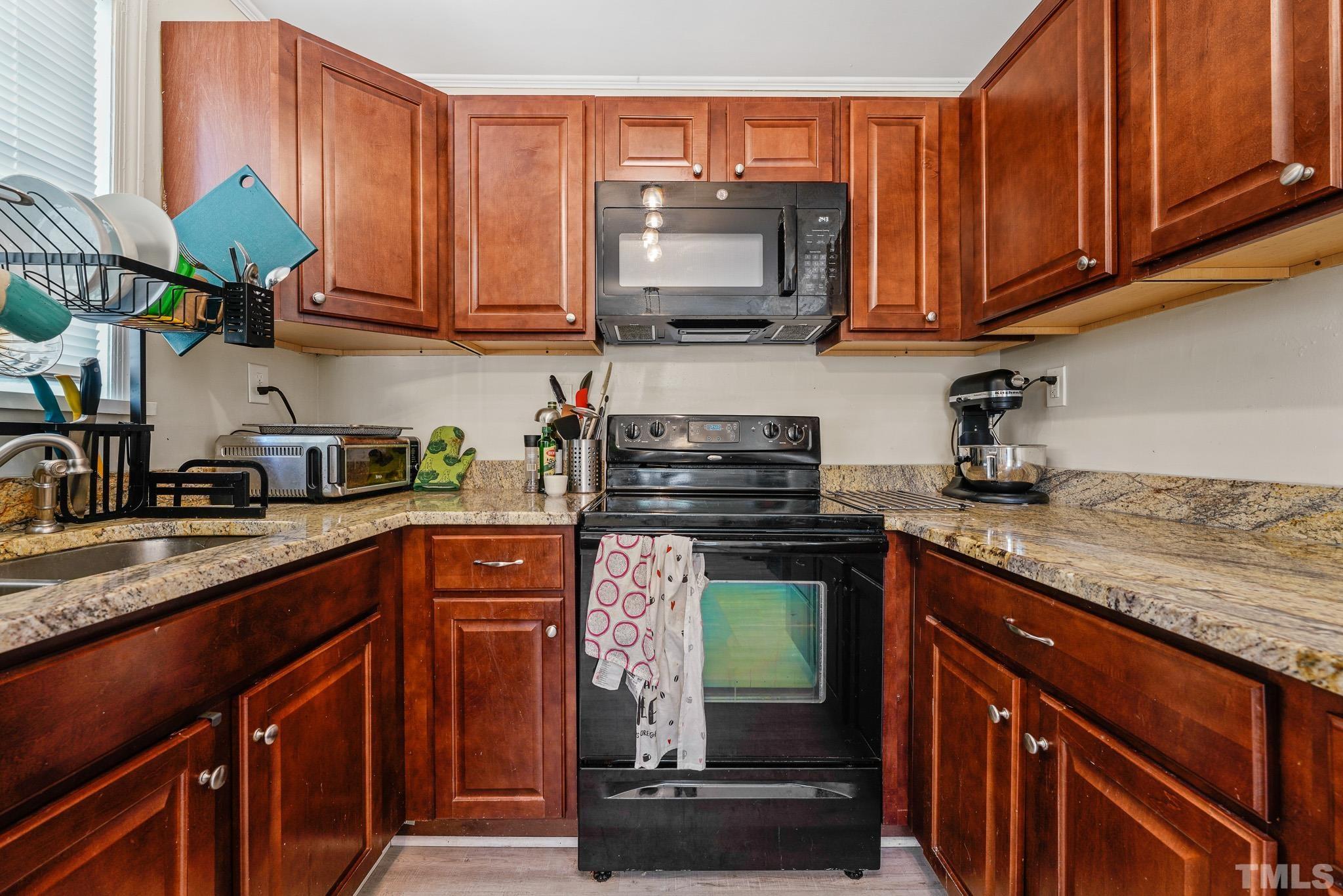 625 Coleman Street Raleigh, NC 27610 - Photo 9 of 22 a kitchen with stainless steel appliances granite countertop a stove top oven a sink dishwasher and a microwave with wooden cabinets