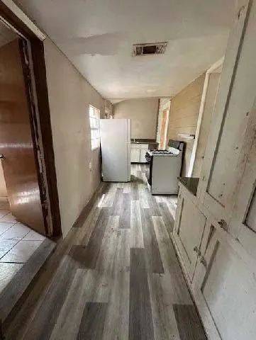 a living room with couches and kitchen view with wooden floor