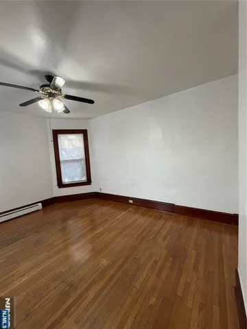 an empty room with wooden floor chandelier fan and windows