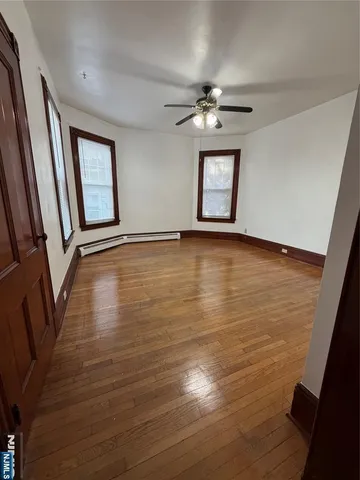 a view of an empty room with wooden floor and window
