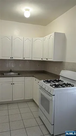 a kitchen with granite countertop white cabinets and stainless steel appliances