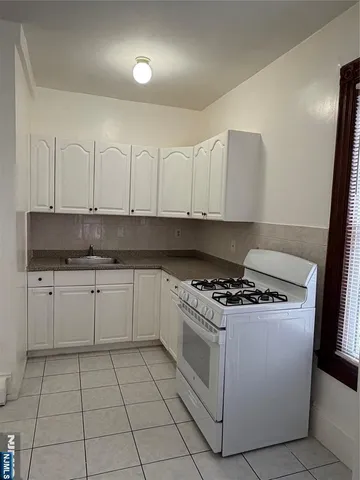 a white kitchen with granite countertop a stove a sink and dishwasher