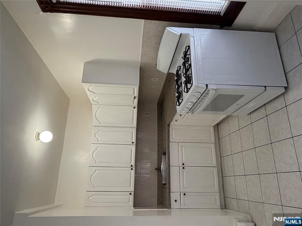 64 Knickerbocker Road, Unit 2 2 Englewood, NJ 07631 - Photo 7 of 27 a white kitchen with granite countertop a stove a sink and dishwasher