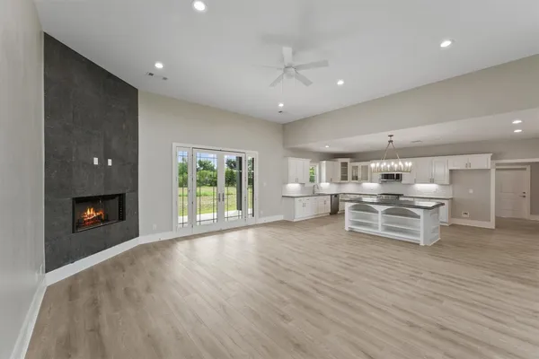 an empty room with kitchen view and a fireplace