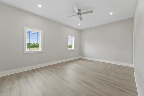 a view of an empty room with a window and wooden floor