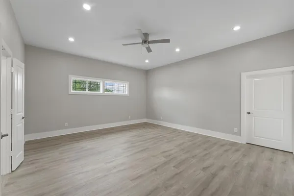 an empty room with wooden floor ceiling fan and windows
