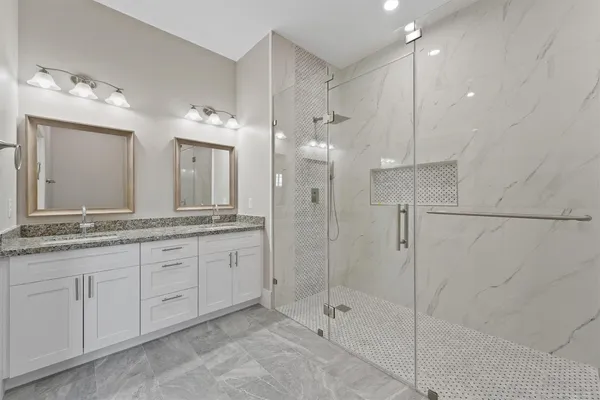 a bathroom with a granite countertop sink mirror and a shower