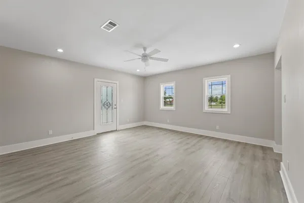 an empty room with wooden floor and windows