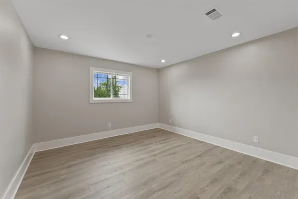 an empty room with wooden floor and windows