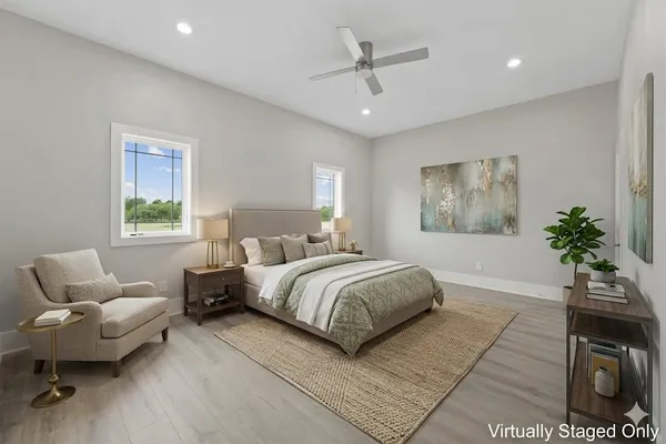 a spacious bedroom with a bed a couch and potted plant on the dresser