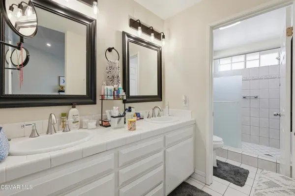 a bathroom with a double vanity sink mirror and shower