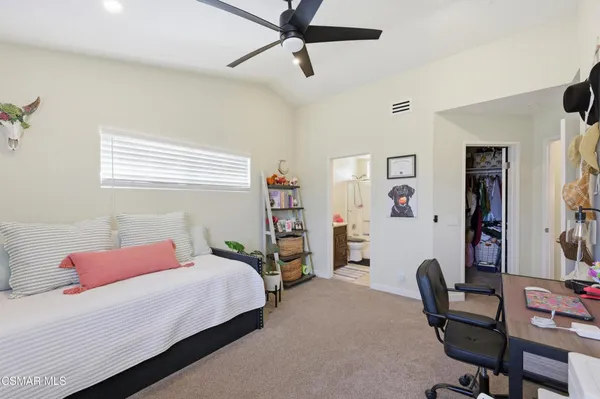 a bedroom with a bed a desk and chair with the bookshelf
