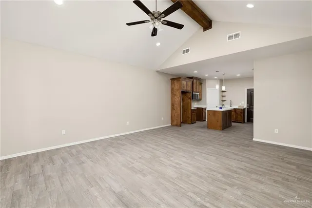 an empty room with kitchen and ceiling fan ceiling fan