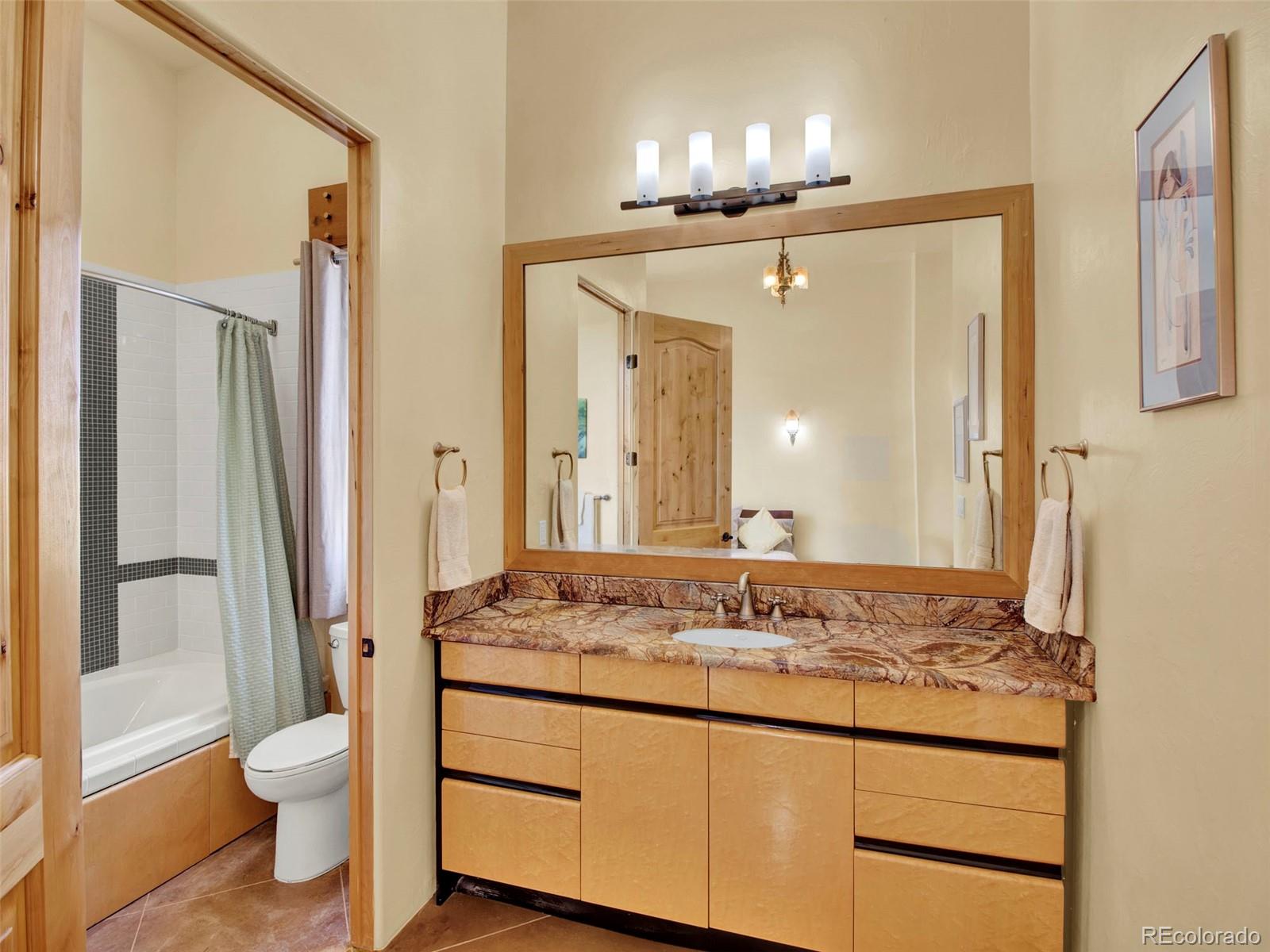 5549 Yulle Road Bennett, CO 80102 - Photo 39 of 47 a bathroom with a granite countertop sink toilet a mirror and shower