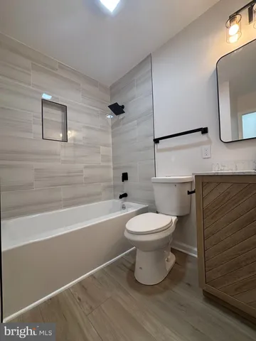a bathroom with a toilet a sink a mirror and bathtub