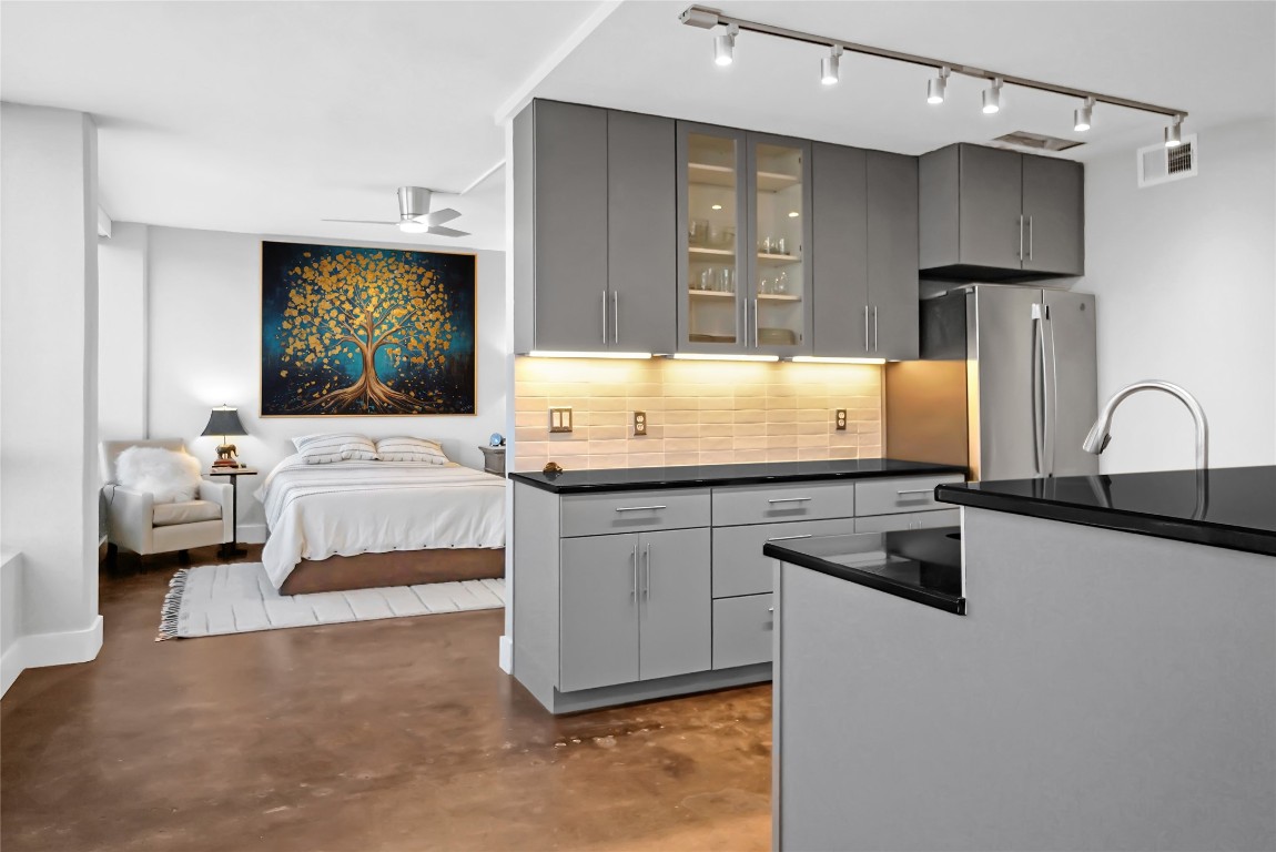 1212 Guadalupe Street, Unit 1004 Austin, TX 78701 - Photo 18 of 33 Kitchen with gray cabinetry, concrete floors, backsplash, and glass insert cabinets