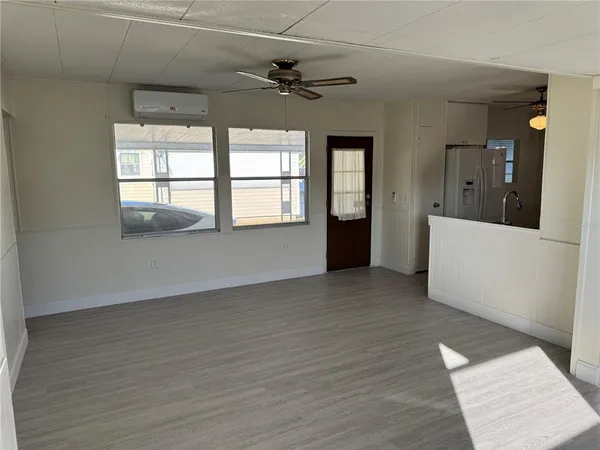 a view of an empty room with a window and wooden floor