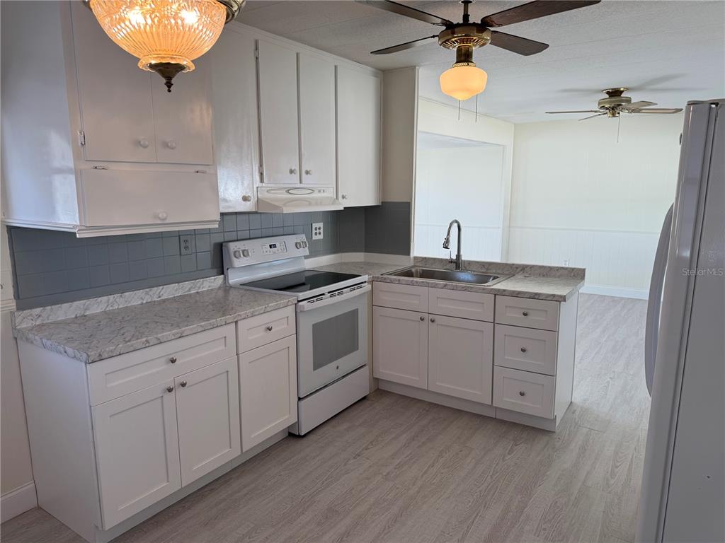 10805 Tioga Drive Port Richey, FL 34668 - Photo 6 of 15 a kitchen with white cabinets and white appliances