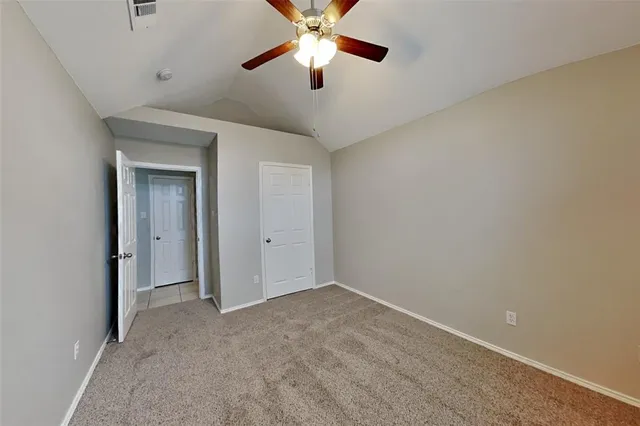 a view of an empty room and chandelier fan