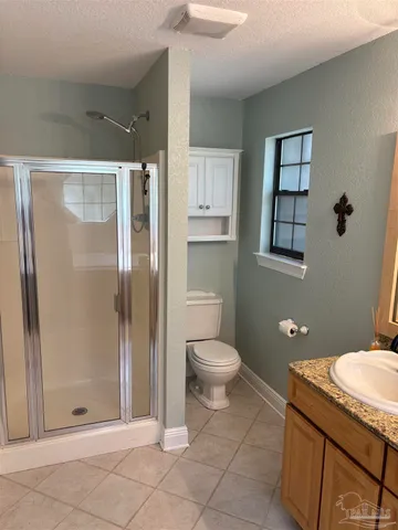 a bathroom with a granite countertop sink a toilet and shower