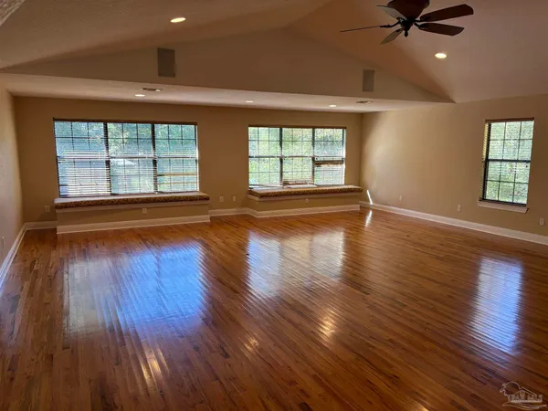a view of empty room with wooden floor and fan
