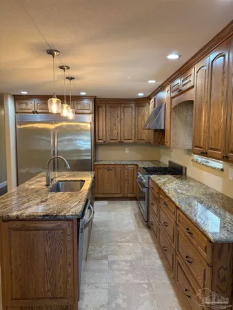 a kitchen with granite countertop a sink a counter top space and cabinets