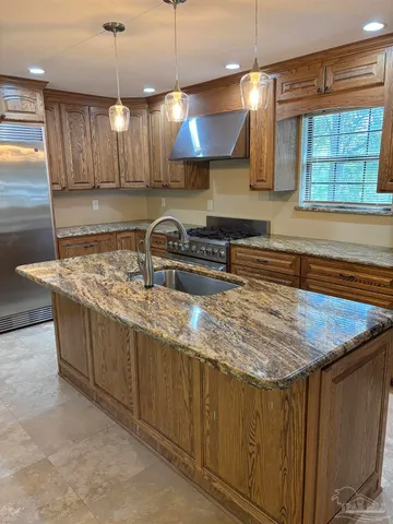 a kitchen with stainless steel appliances granite countertop a sink a stove and a refrigerator
