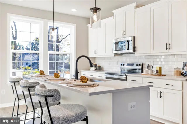 a kitchen with stainless steel appliances kitchen island granite countertop a table chairs sink and cabinets