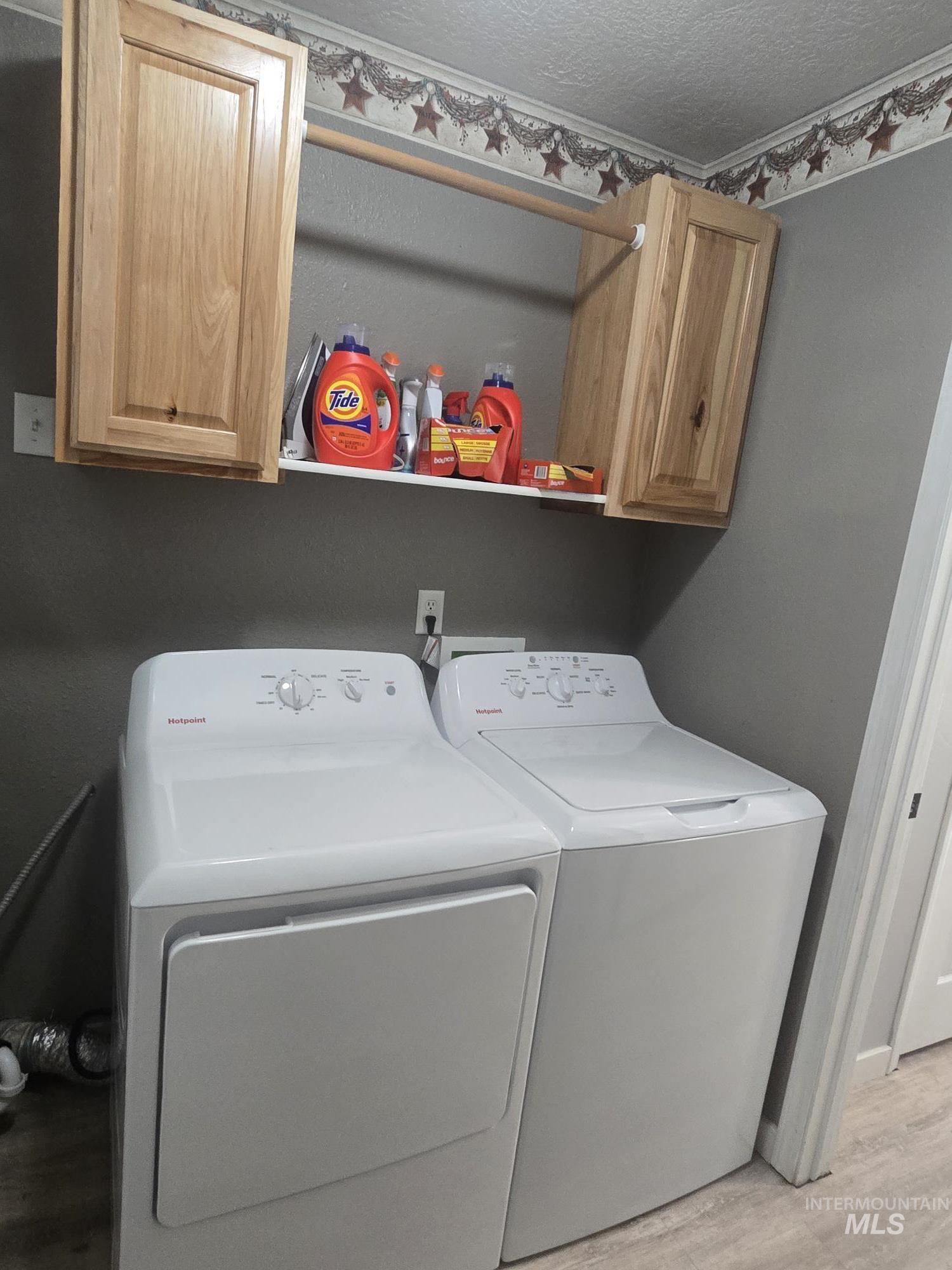 2480 West 9th Street Weiser, ID 83672 - Photo 16 of 17 Dedicated laundry area featuring a white washer and dryer, wood-finish wall cabinetry, and a clothes hanging rod