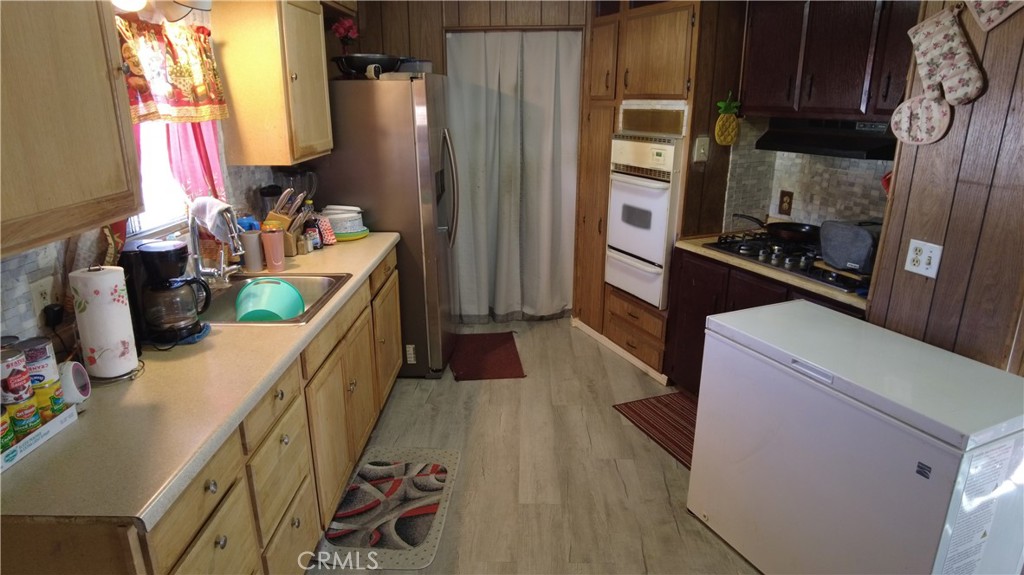 4561 Adobe Road, Unit 1 Twentynine Palms, CA 92277 - Photo 32 of 57 a kitchen with stainless steel appliances a stove a refrigerator a sink dishwasher and wooden cabinets with wooden floor