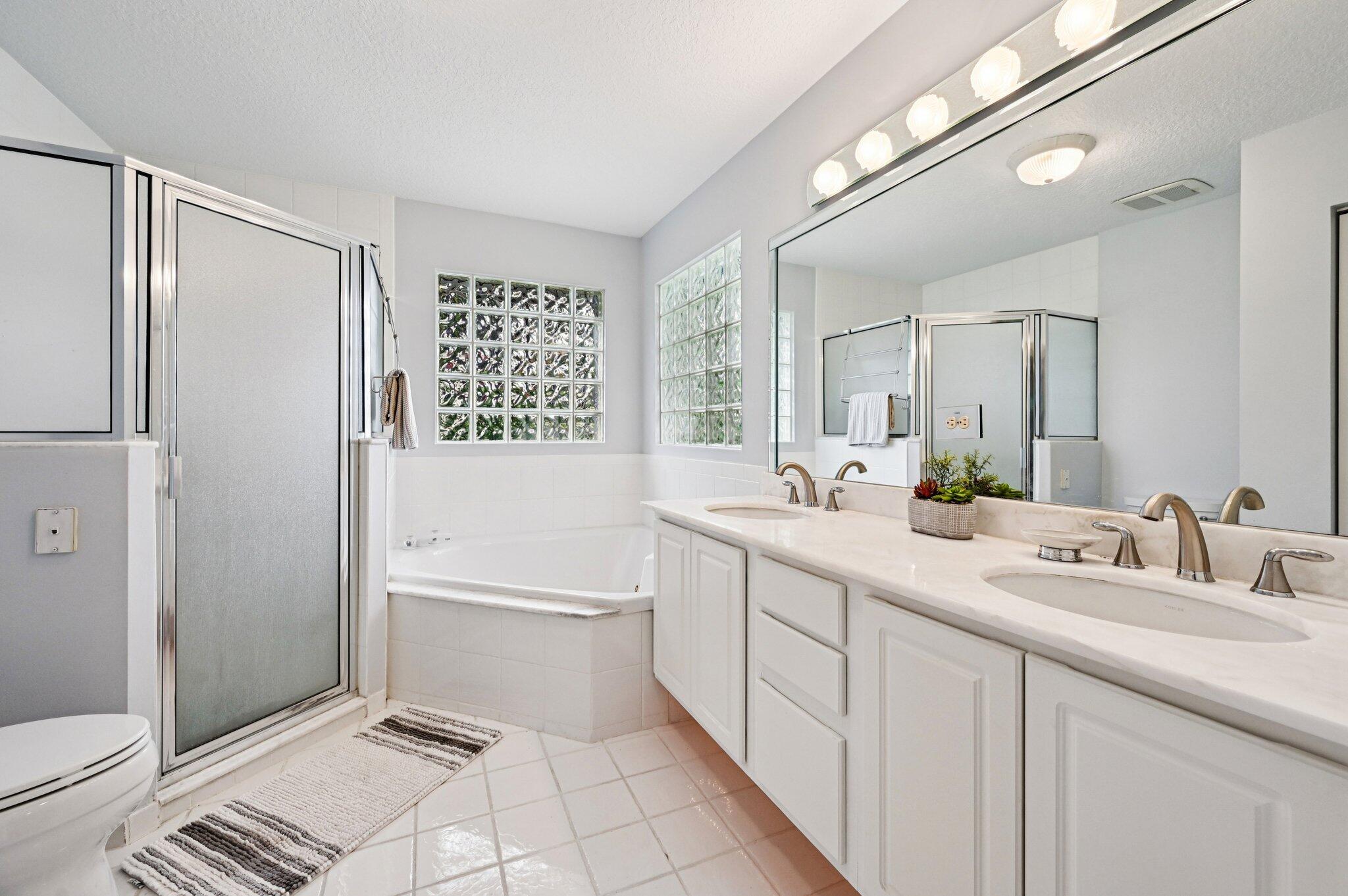 231 Sparrow Point Jupiter, FL 33458 - Photo 28 of 65 a spacious bathroom with a double vanity sink a toilet mirror and a shower