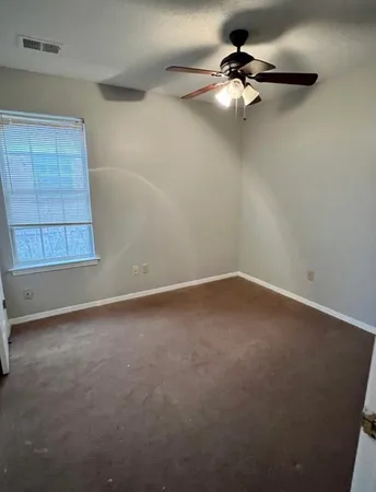 en empty room with windows and fan