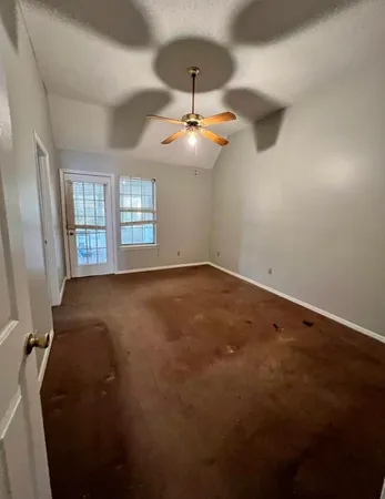 an empty room with windows and ceiling fan