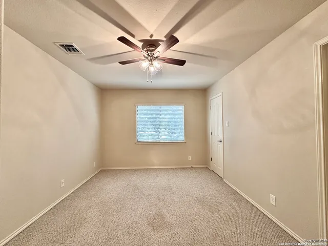 an empty room with windows and fan