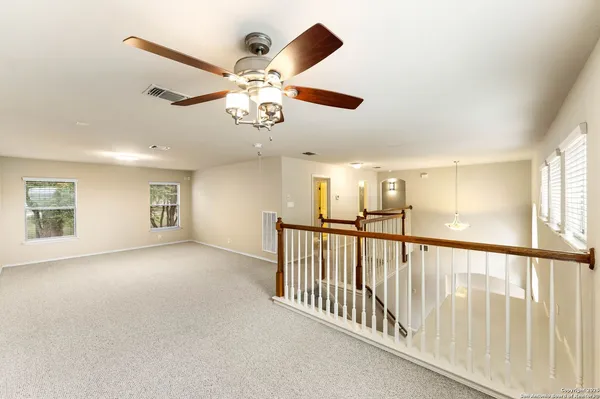 an empty room with ceiling fan and windows