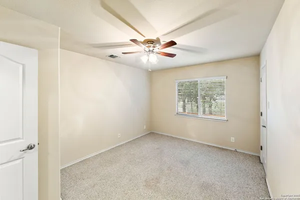 an empty room with windows and fan