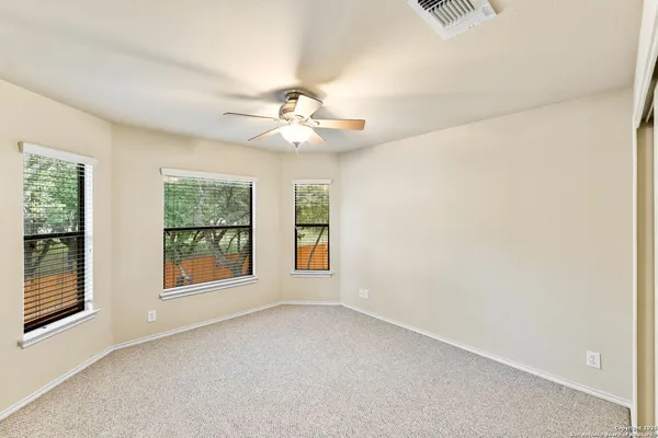 an empty room with windows and chandelier fan