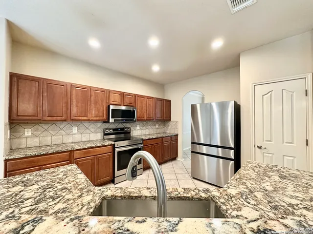 a kitchen with stainless steel appliances granite countertop a refrigerator sink and stove