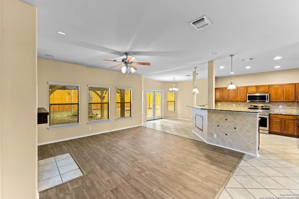 a view of an empty room with window and kitchen view