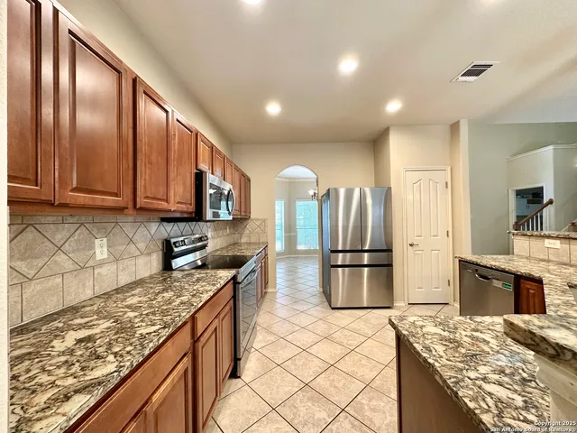 a kitchen with stainless steel appliances granite countertop a refrigerator stove and sink