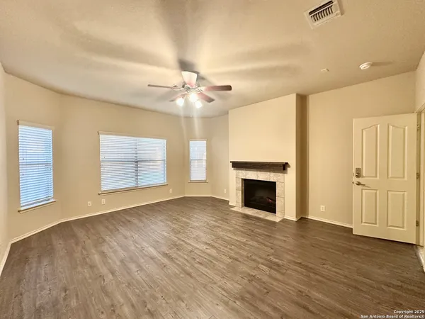 an empty room with windows fireplace and wooden floor