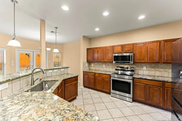 a large kitchen with stainless steel appliances granite countertop a large stove a sink and a microwave