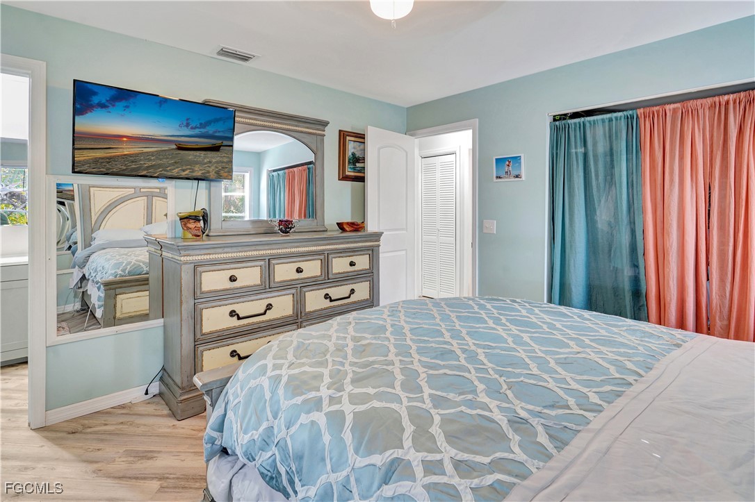 5887 Kingfish Road Bokeelia, FL 33922 - Photo 12 of 34 a bedroom with a bed and a dresser with mirror