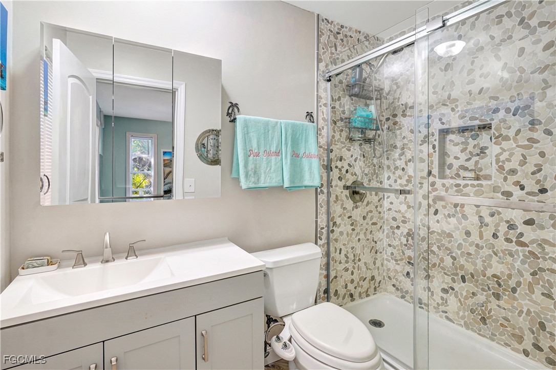 5887 Kingfish Road Bokeelia, FL 33922 - Photo 19 of 34 a bathroom with a sink a toilet and shower curtain
