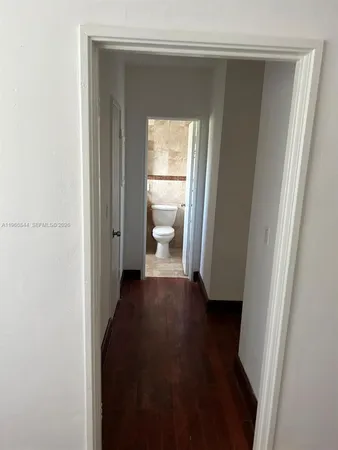 a view of a hallway with wooden floor and a cabinet