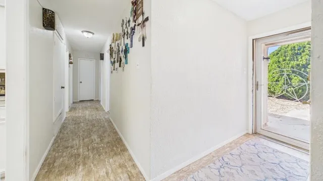 a view of a hallway with wooden floor and a bathroom